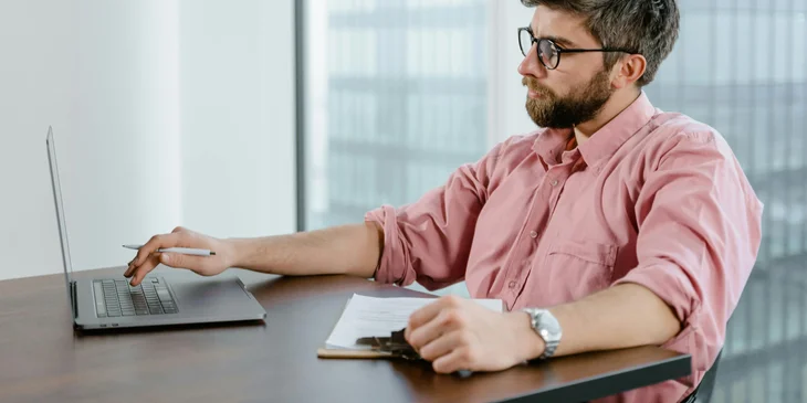A compensation analyst reading and analyzing data on his laptop.