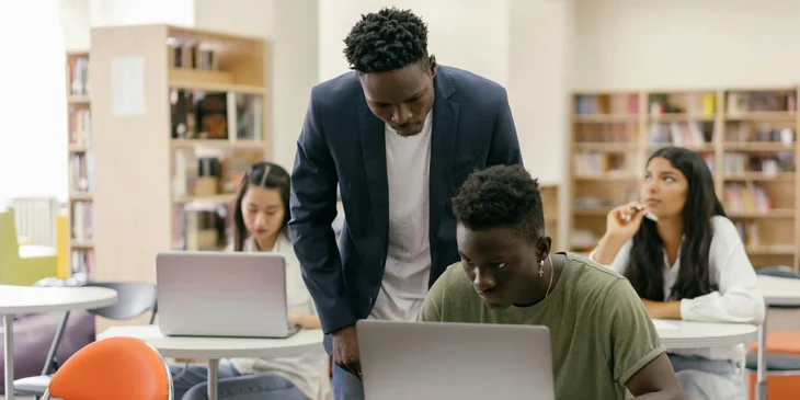 A computer teacher guiding his students on how to run an application.