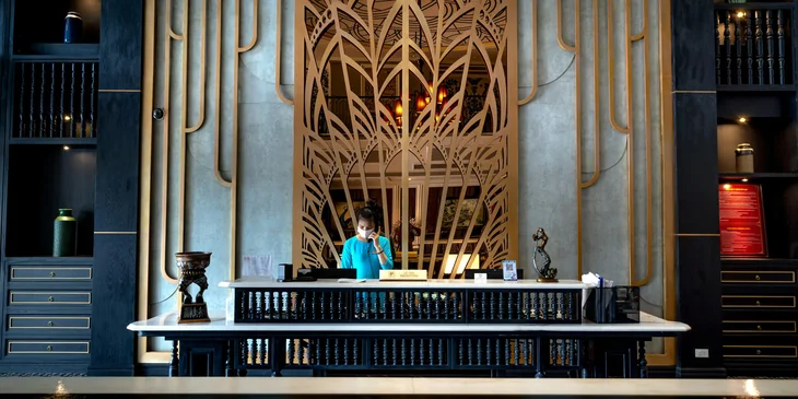 A female concierge speaking on the phone at the reception desk.