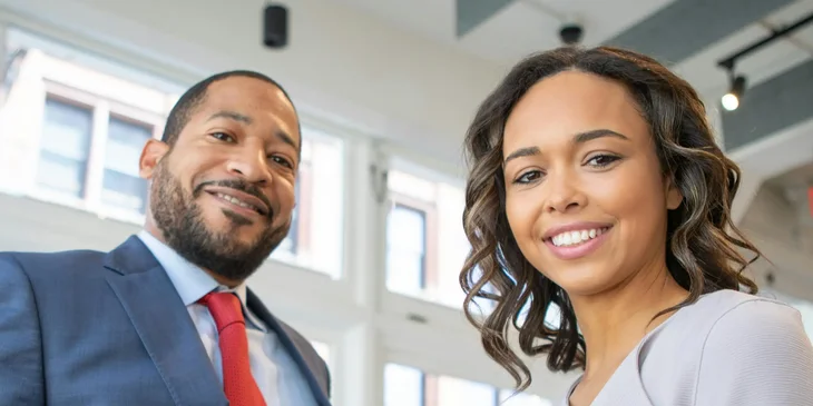 A man and woman smiling inside a building.