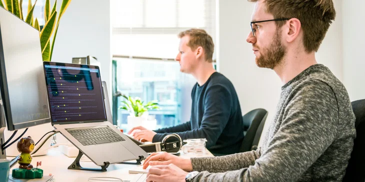 Coworkers sitting on a chair while working.