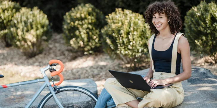 A cheerful female using a laptop outdoors.