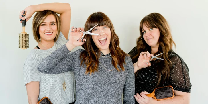 Three women holding a scissor and a brush.