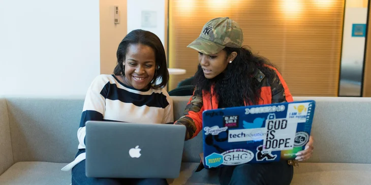 Two women collaborating while working on a laptop.
