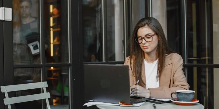 A woman working on her laptop outside.