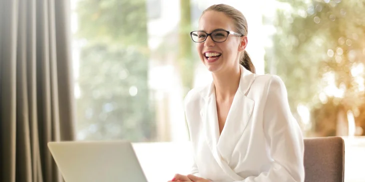 A woman smiling while sitting at her desk.