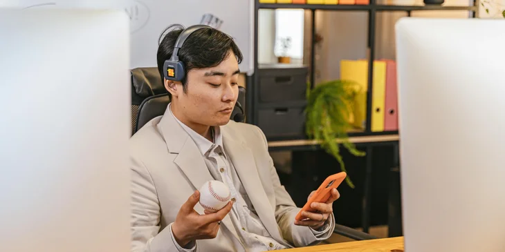 A man holding a ball while using his mobile phone.