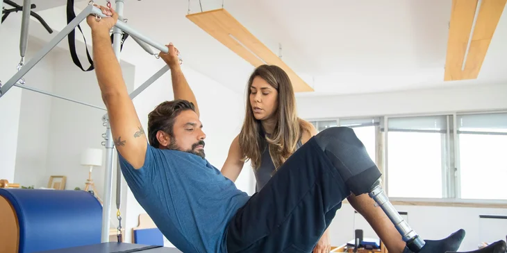 A man performing strength-training exercises under the guidance of a coach.