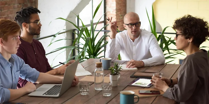 A CTO deliberating with his team while sitting in the conference room.