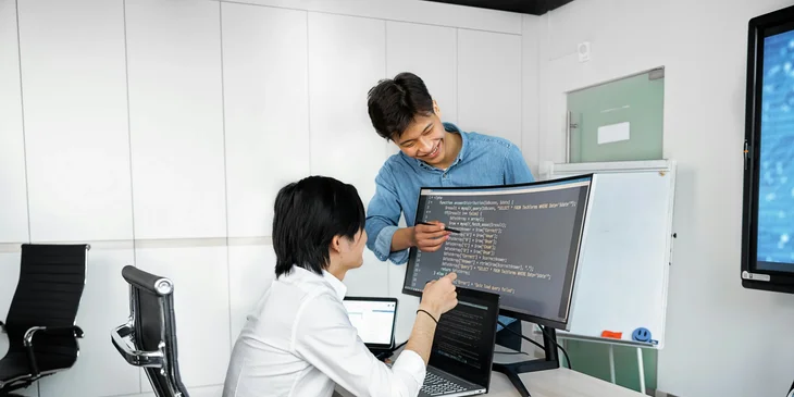 Two young happy professionals working in an office.
