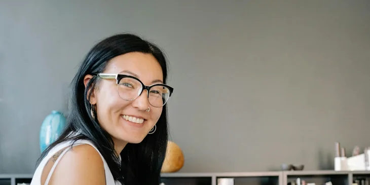 A woman in a white top smiling at the camera.