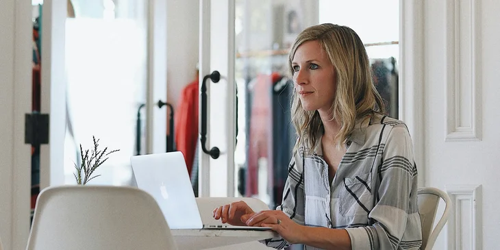 A woman sitting on a chair in front of a laptop.