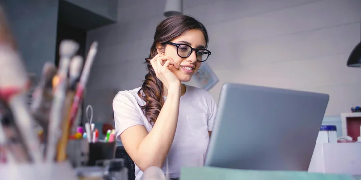 A woman smiling in front of a laptop.