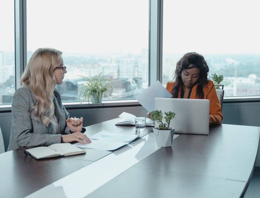 Development Coordinator checking files while listening to colleague planning an event