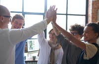 Un grupo de personas alzando sus manos en una actividad para mejorar el trabajo en equipo.