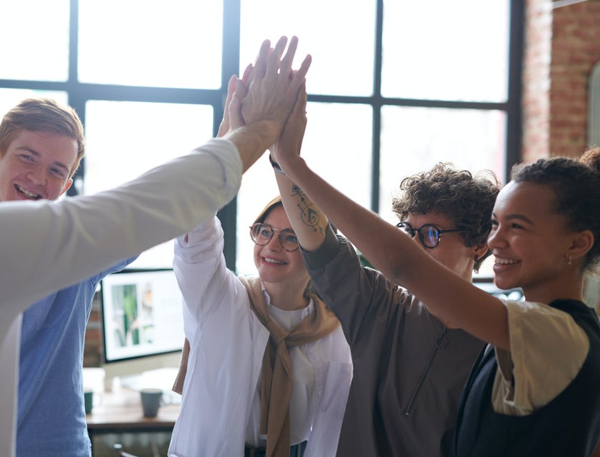Un grupo de personas alzando sus manos en una actividad para mejorar el trabajo en equipo.