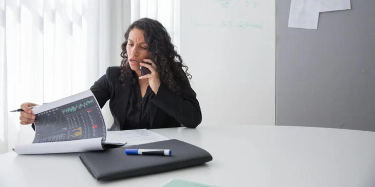 A business development director speaking on the phone regarding a document at hand.