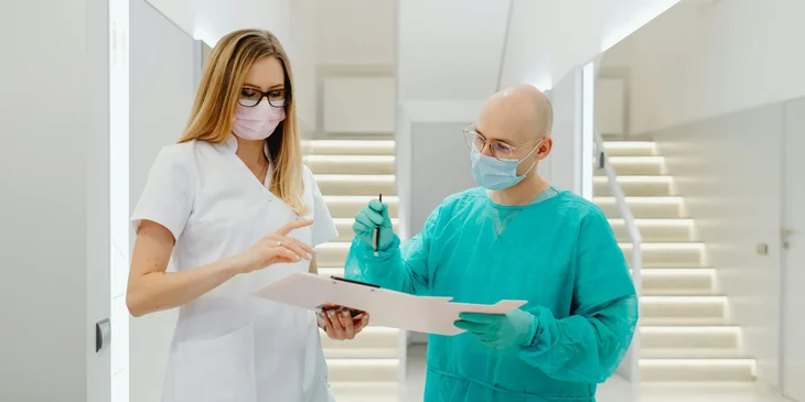A female nursing director reviewing the document presented by the male nurse.
