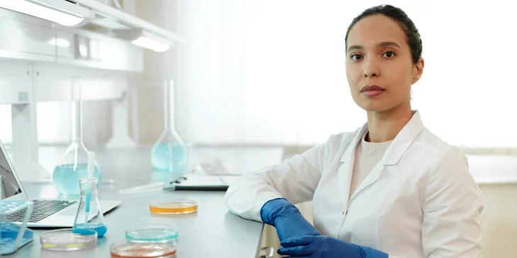 A female scientist in a white lab coat, about to conduct an experiment.