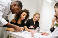 Un grupo de colegas platicando sobre unas notas.