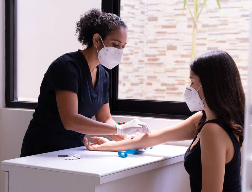 Un asistente médica limpiando el brazo de una paciente.