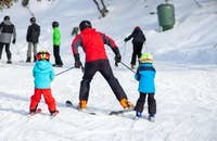 Un istruttore di sci che insegna a due bambini.