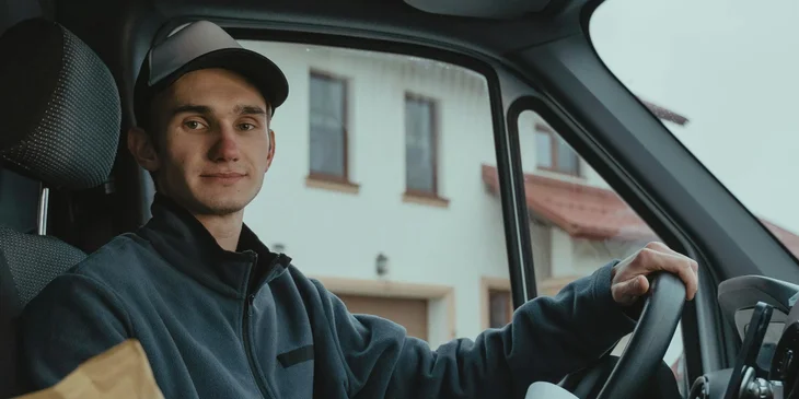 A delivery man sitting on driver's seat.