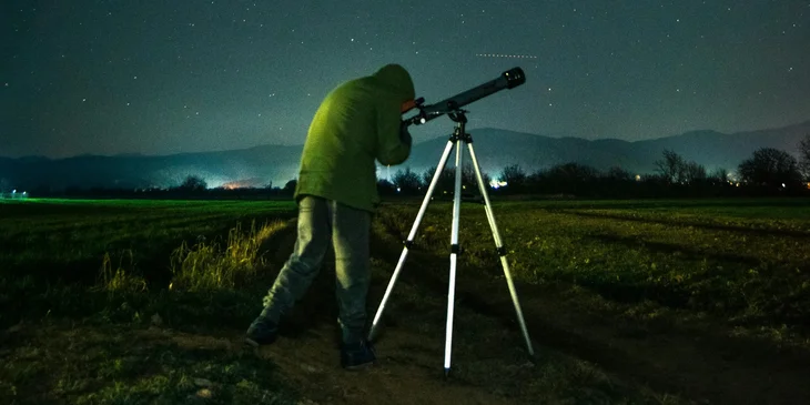 An astronomer gazing through a telescope on a starry night.