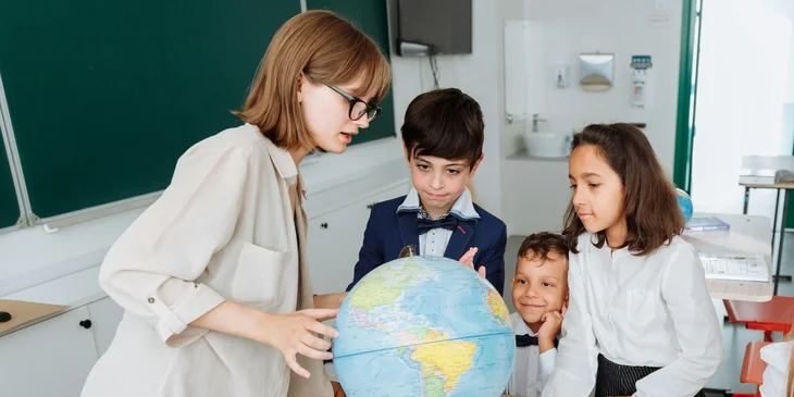 A teacher explaining countries around the world using a globe.