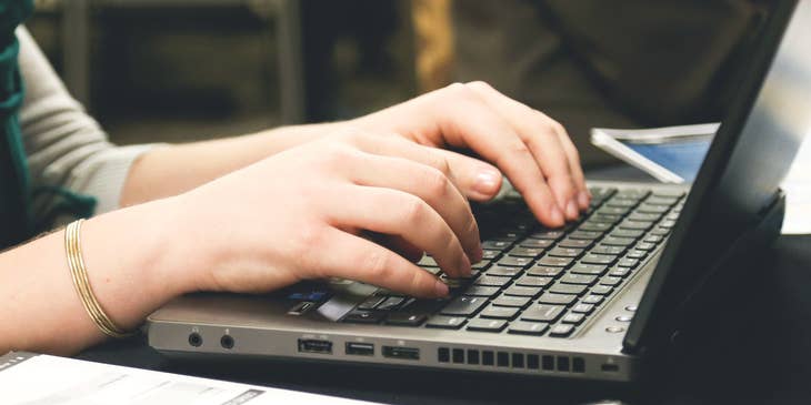 Dettaglio delle mani di una donna mentre scrive una email di dimissioni.