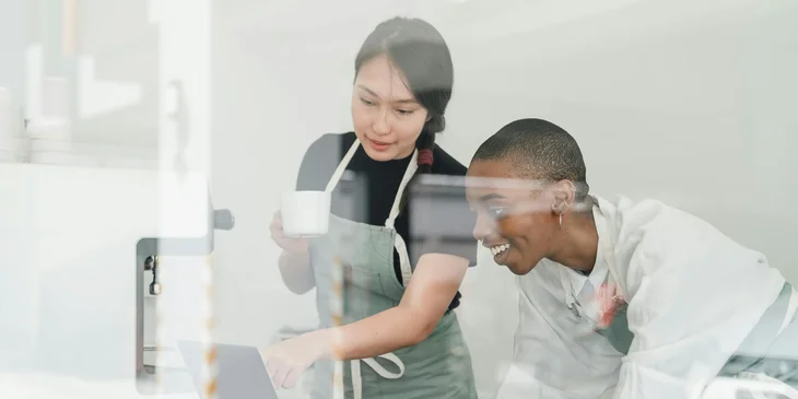 A lady worker helps her coworker who is struggling to save a document.