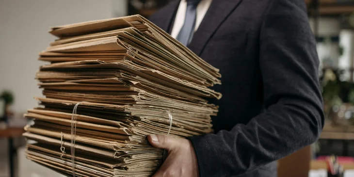 La mano de un ejecutivo sosteniendo formularios de información de los empleados.