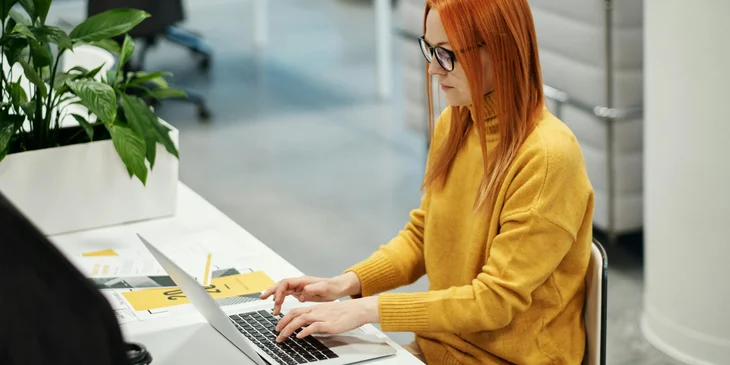 A woman creating employee recognition ideas on her laptop.