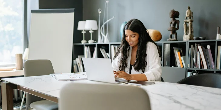 A female employee relations specialist in an office setting, using her laptop.