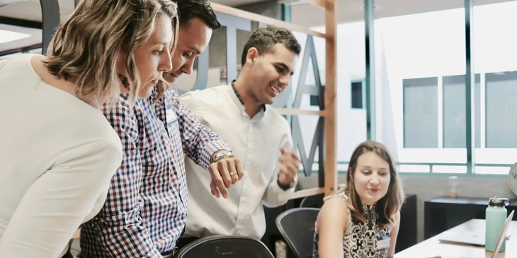 Employees standing around a desk.