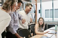 Funcionários em pé ao redor de uma mesa.