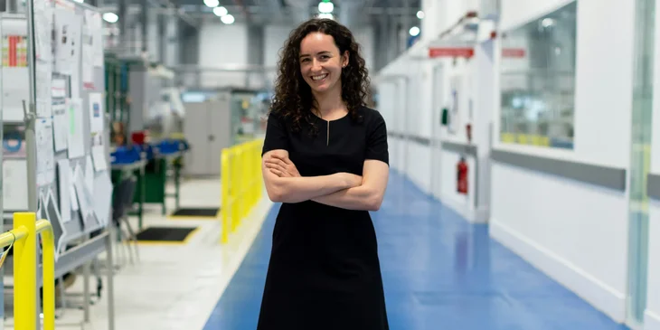 A woman in black dress standing on a blue floor.