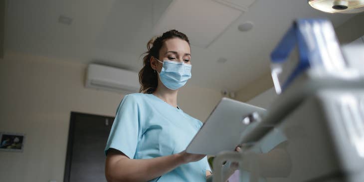 An ER tech reading the medical file of a patient in emergency care.