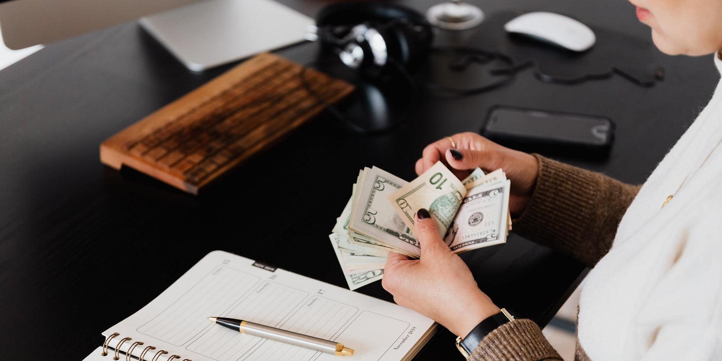 Person counting money with a notebook on the table