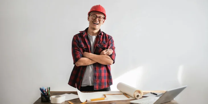 A man wearing a safety helmet standing in front of a table.