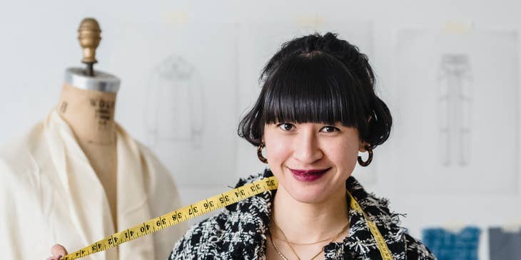 A fashion designer holding a measuring tape.