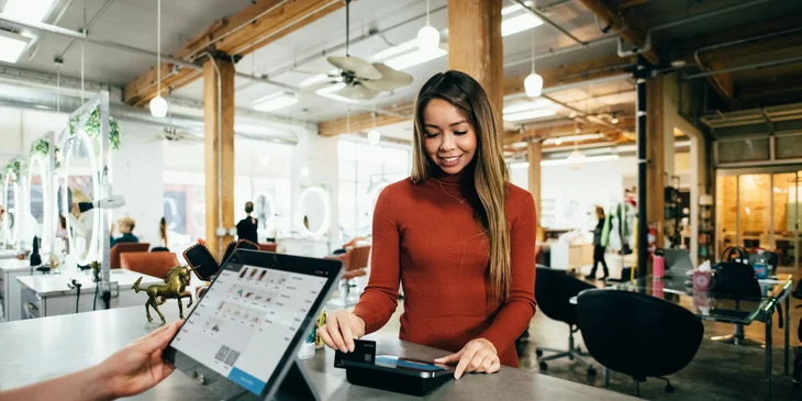 A female customer swiping her card at the POS terminal to make a payment.