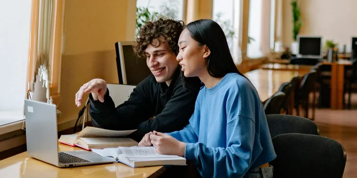 Two students discussing a project at a desk.