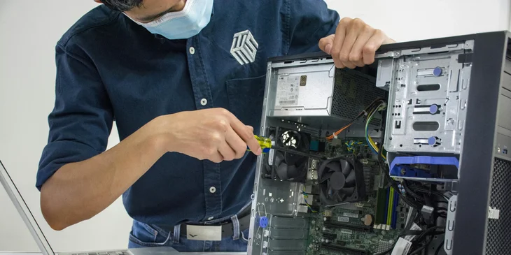 A field service technician repairing a broken computer fan inside a CPU.