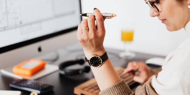 A woman doing financial planning on her computer with a pen in hand.