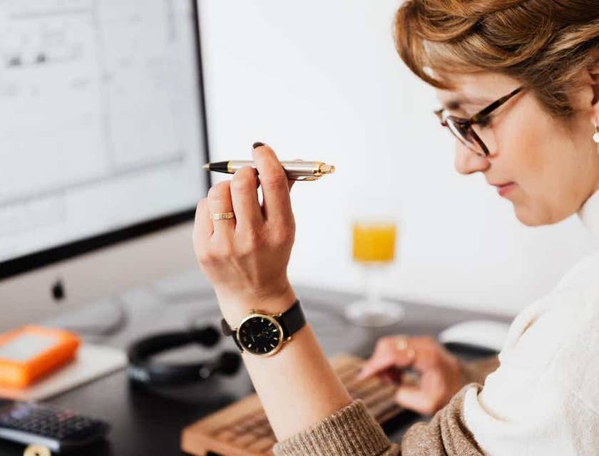 Una mujer haciendo planificación financiera en su ordenador con un bolígrafo en la mano.