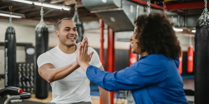 A fitness instructor sitting in a gym with a client.