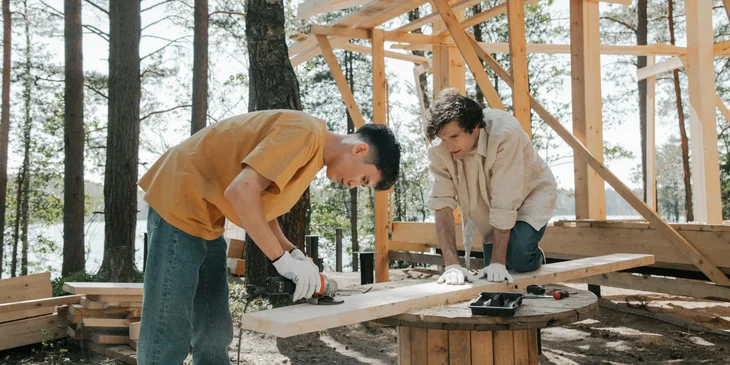 Framing carpenters sanding wood for framing.