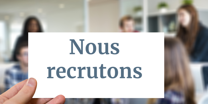 Un employeur tenant une pancarte qui dit "Nous recrutons" en anglais.