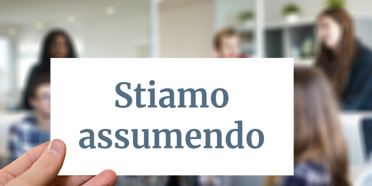 Un datore di lavoro che tiene in mano un cartello con scritto "stiamo assumendo" in inglese.